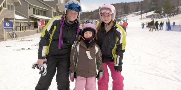 Two Ski Instructor with a student outside at the base of slope