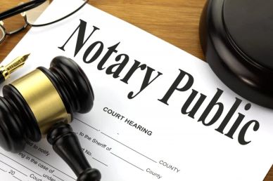 A notary public document with a gavel and glasses on a wooden surface.