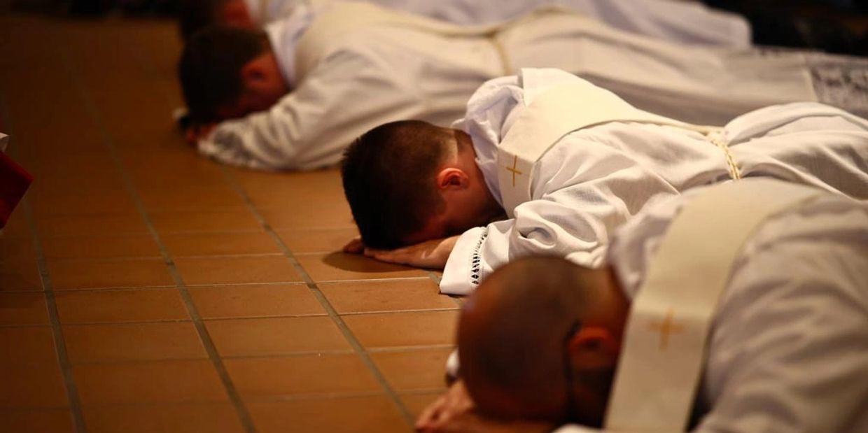 Image of Priests laying face down at the altar during their ordination. 