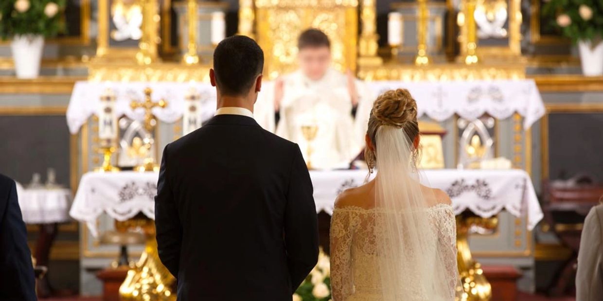 Image of a bride and groom facing the priest on the altar. 