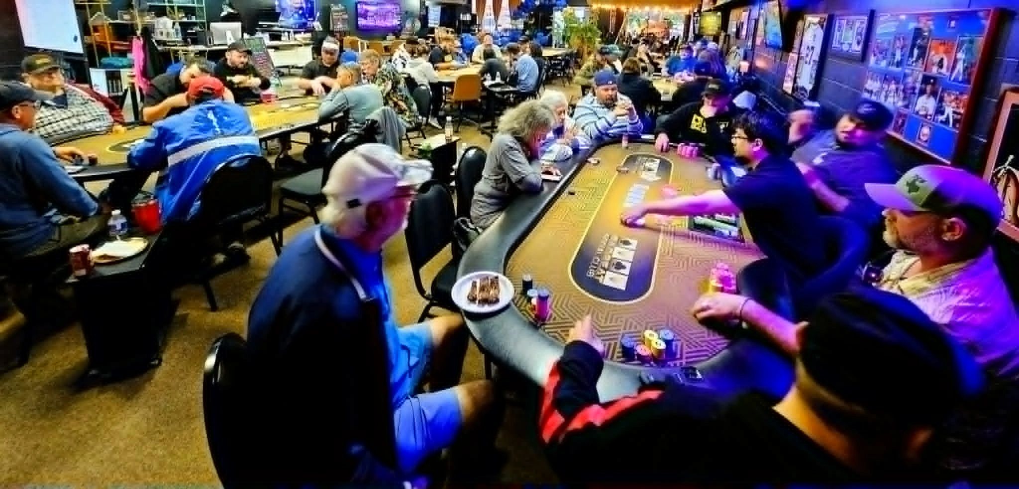 People playing poker at a busy casino table with chips and cards.