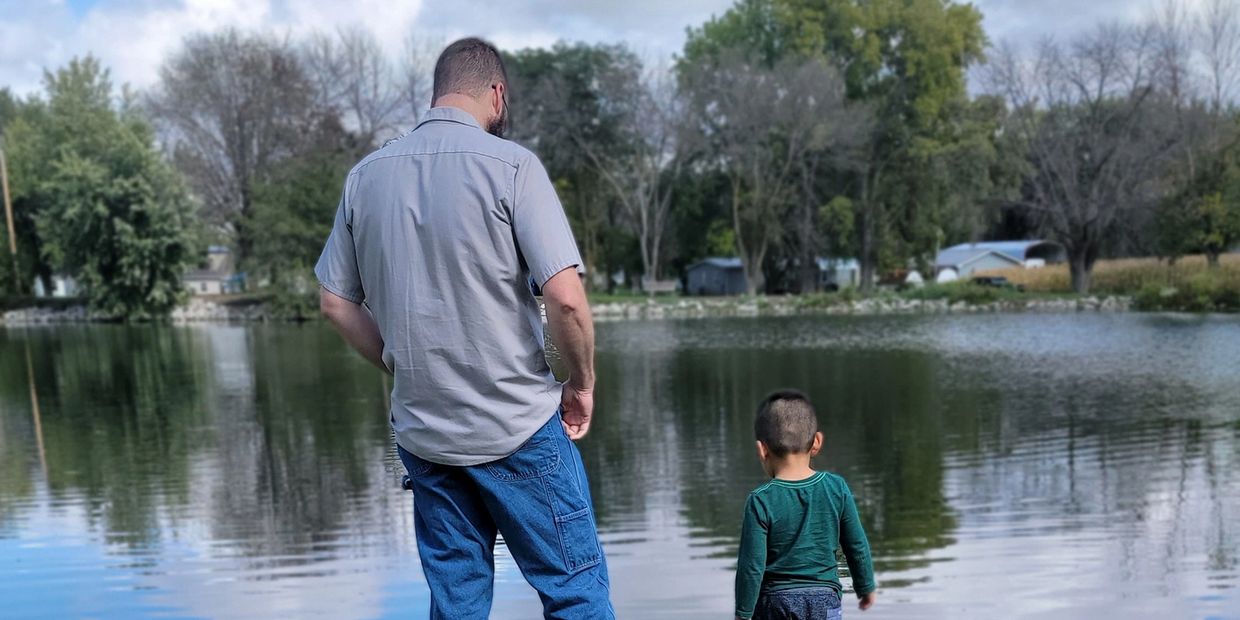 father and son standing by a pond