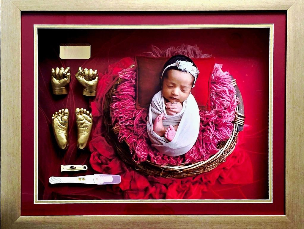 Newborn baby portrait with golden hand and foot casts.