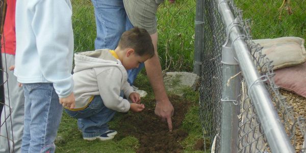 Children helping Jay plant seeds in the garden.