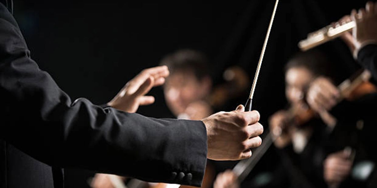 Orchestra conductor's arms conducting an orchestra