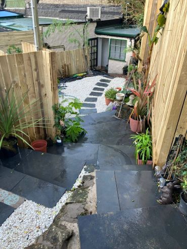 Outdoor staircase leading to a garden patio with plants.