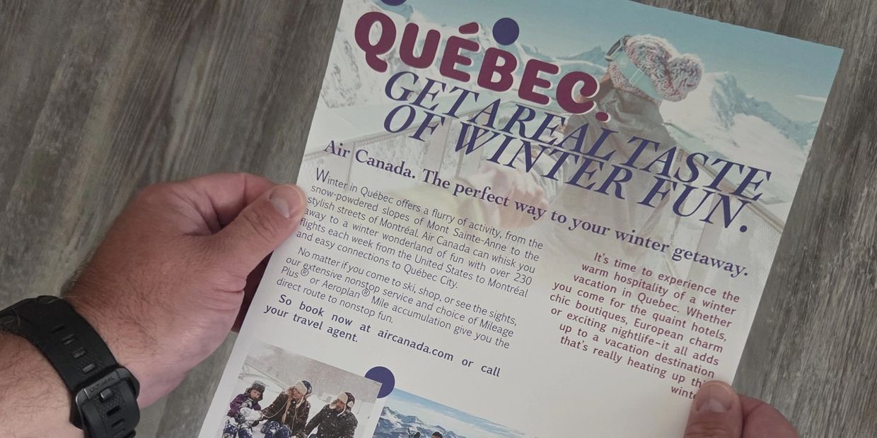 Hands holding a Québec winter travel flyer promoting Air Canada flights.
