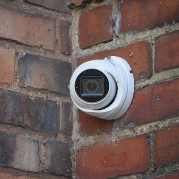 Security camera mounted on a brick wall corner.