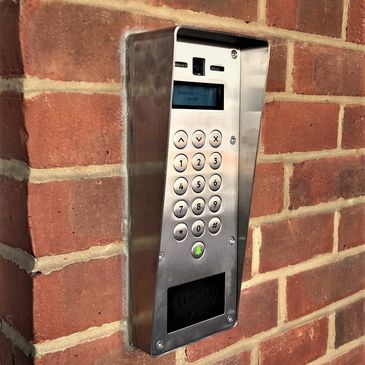Metal keypad access system on brick wall.