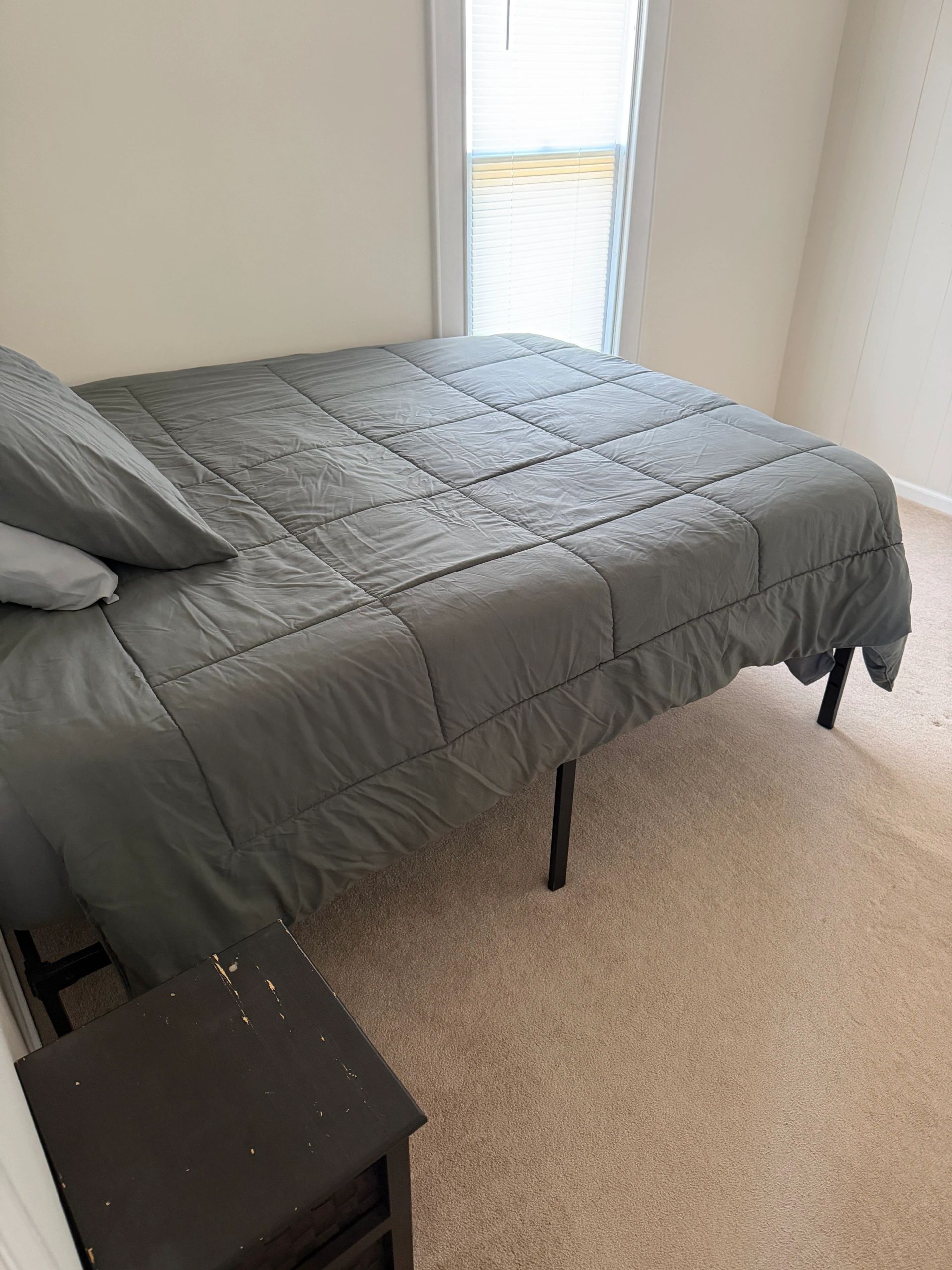 Simple bedroom with a made bed and a small nightstand.