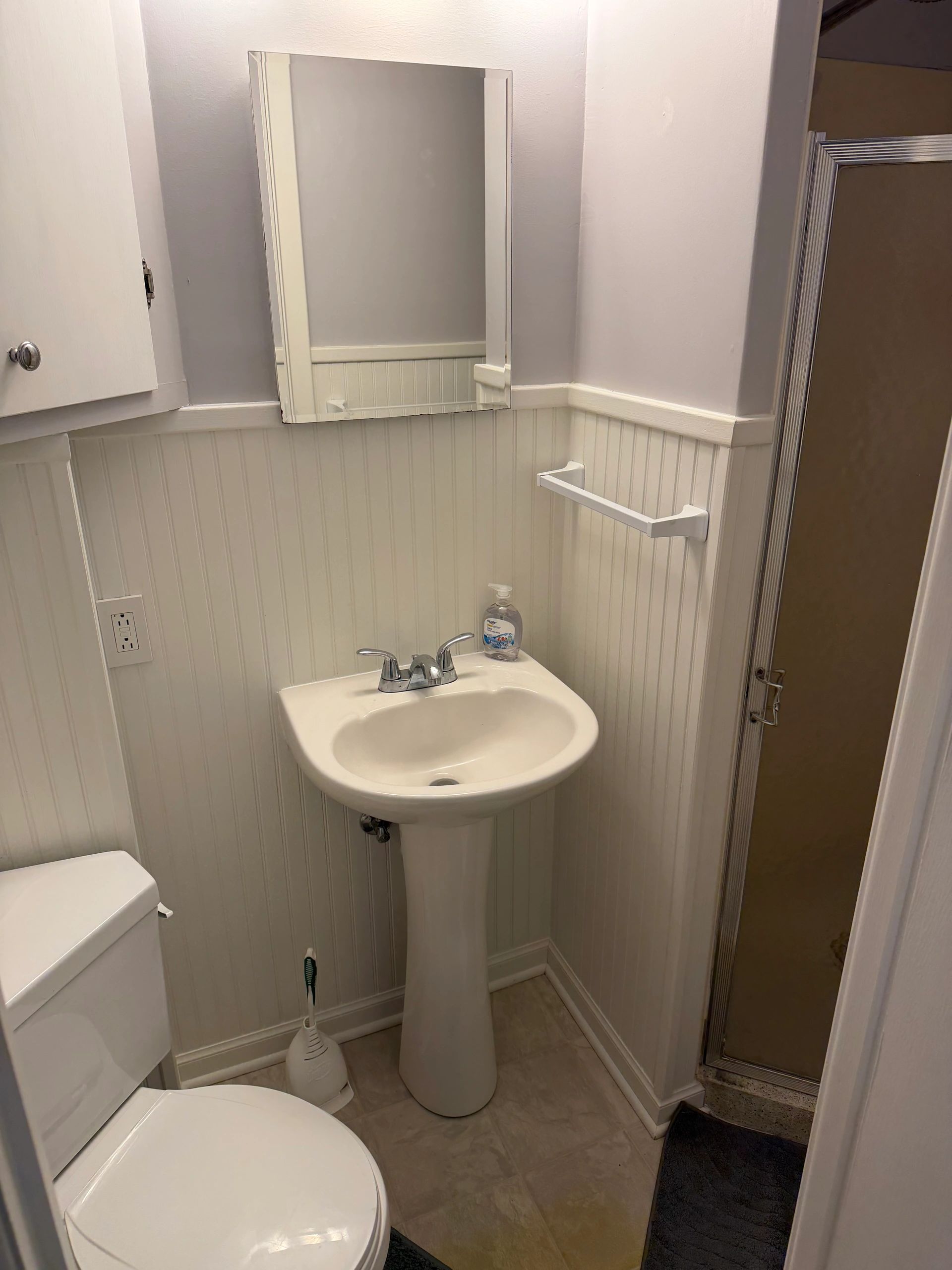 Small bathroom with pedestal sink, toilet, and shower.