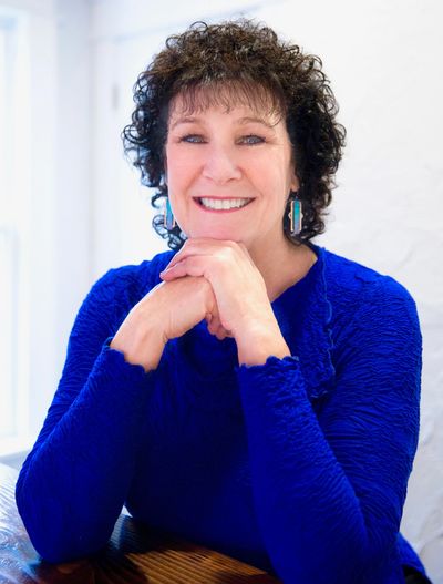 Smiling woman with curly hair in a blue top.