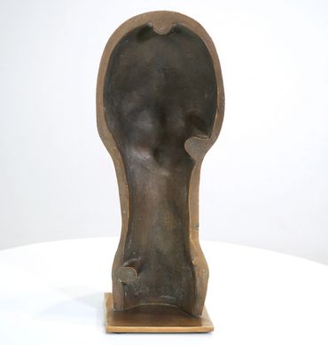 Abstract bronze sculpture with human head outline and smooth interior.