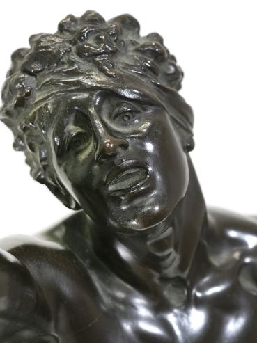 Close-up of a dark bronze male statue with expressive facial features.