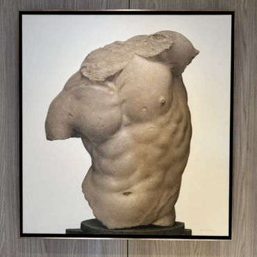 Photograph of an ancient male torso sculpture with missing limbs and head.