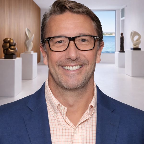 Mark Lukas, founder of Maison Palm Beach, standing in the gallery with fine art and sculpture