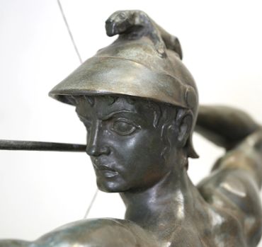 Close-up of a bronze statue of a warrior with a helmet and intense expression.