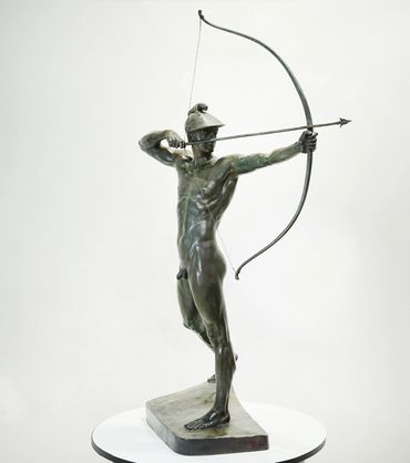 Bronze statue of a nude archer drawing a bow with focused intensity.