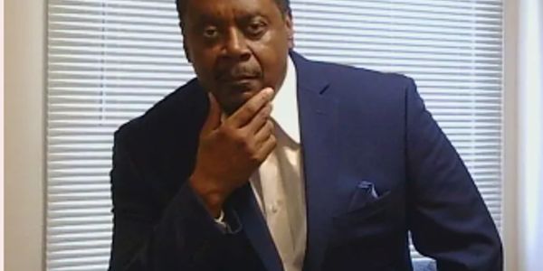 Man in blue suit posing thoughtfully.