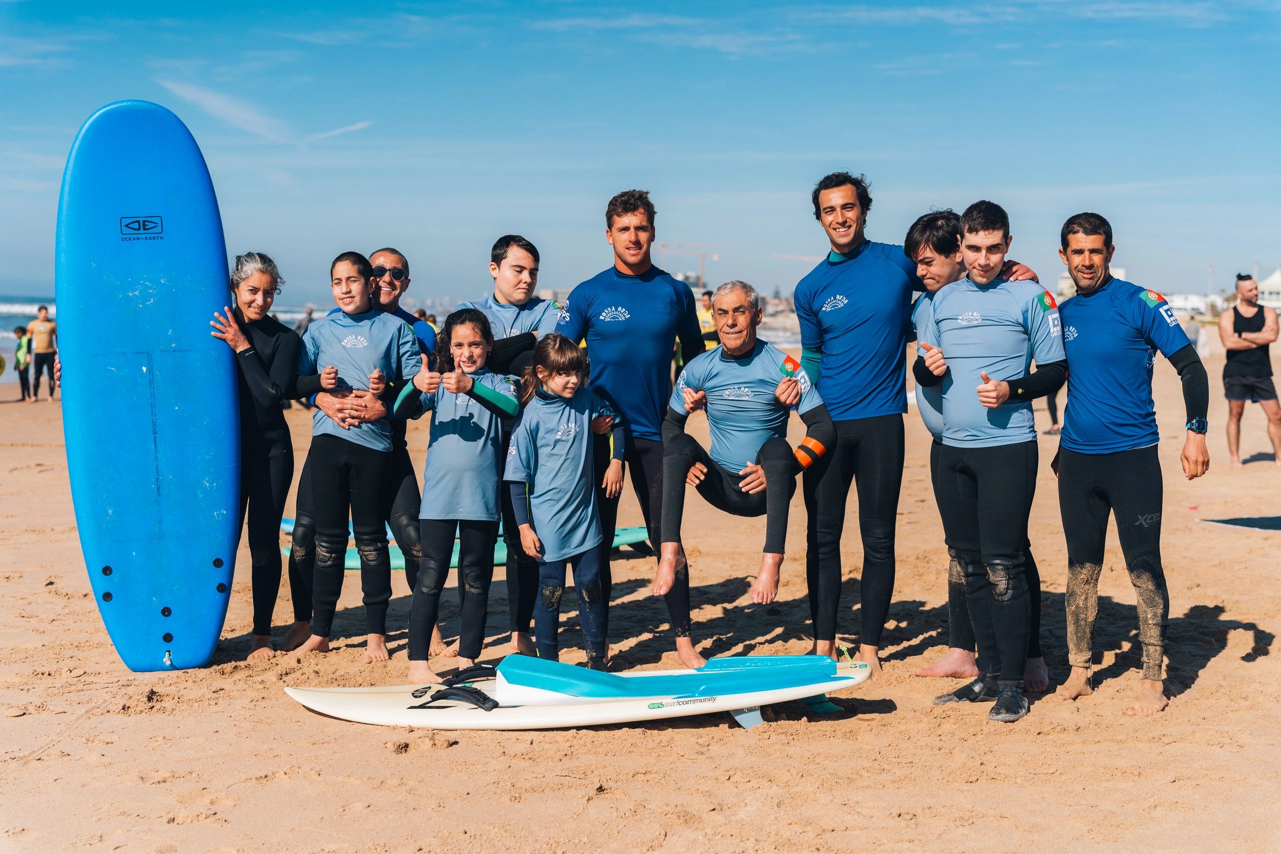 Group of surfers posing happily on the beach with surfboards.