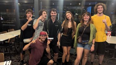 A group of seven friends posing happily indoors at night.