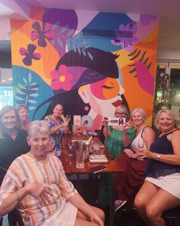 Group of women enjoying drinks at a vibrant mural-adorned restaurant.