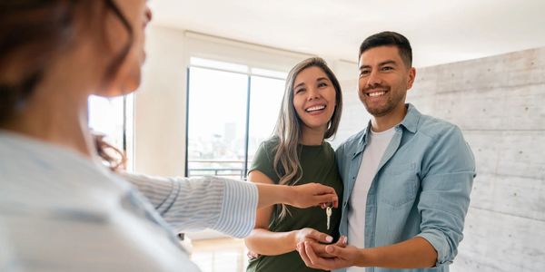 Couple receiving house keys from agent, smiling.