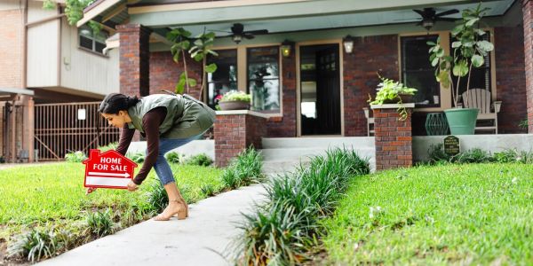 Woman placing a 'Home for Sale' sign.