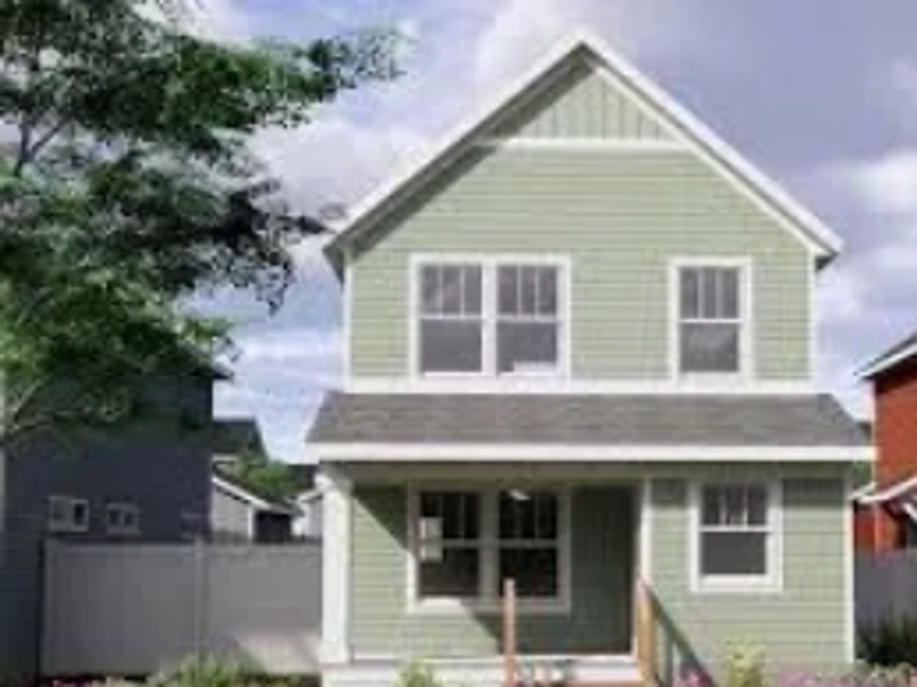 Two-story green house with white trim and a small porch.