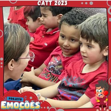 Children in red shirts attentively interacting with a woman at CATT 2023.
