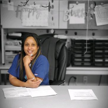 Phlebotomist sitting at a desk, working and smiling.