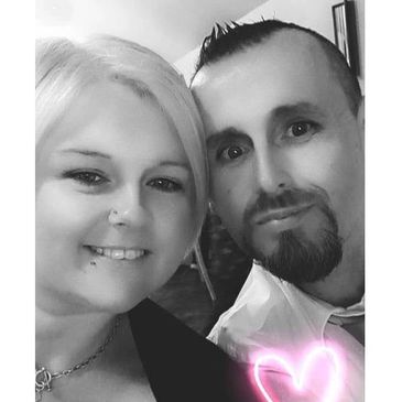 Black and white selfie of a smiling couple with a glowing pink heart.