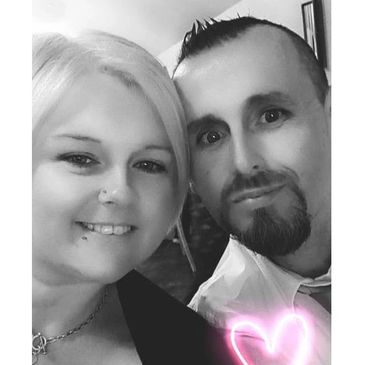 Black and white selfie of a smiling couple with a glowing pink heart.