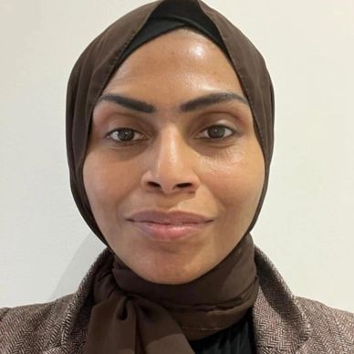 Close-up portrait of a woman wearing a brown hijab and blazer.