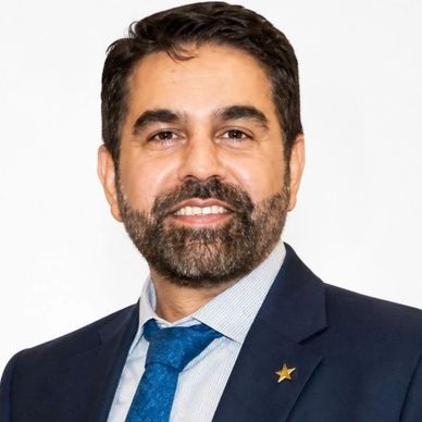 Professional man in suit with a blue tie and a star pin.