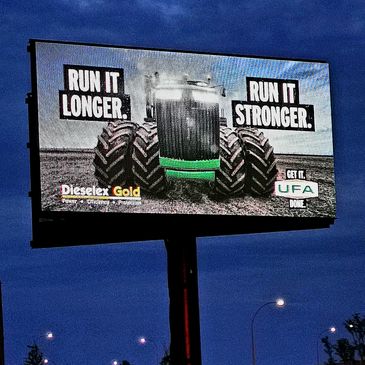 A digital billboard near Highway 43 in Alberta's Peace Region. The image features farm equipment. Te