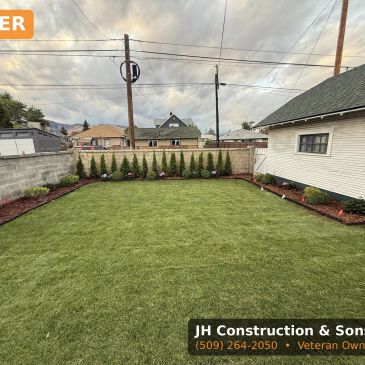 Freshly landscaped backyard with green grass and small bushes.