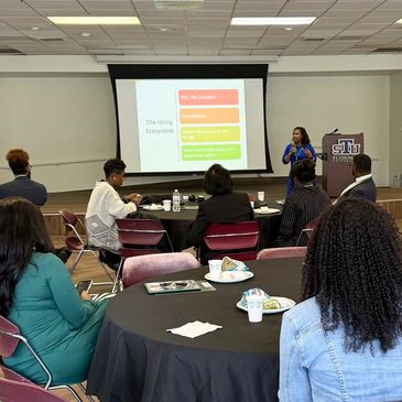 Woman giving presentation to seated audience in a conference room.