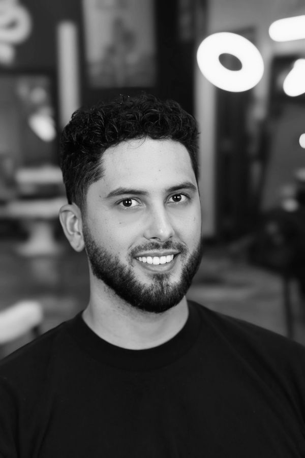 A smiling man with curly hair and a beard in a black shirt.
