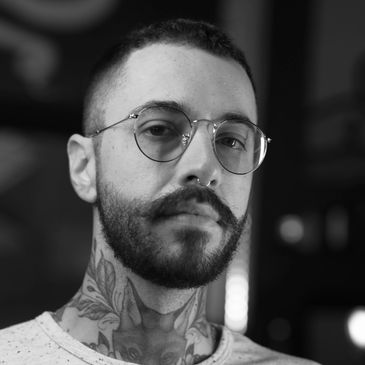Man with glasses and neck tattoos.