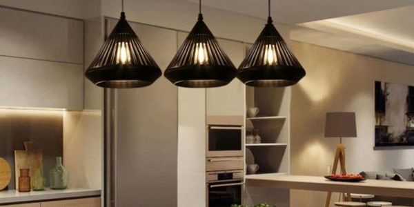 3 black diamond shaped pendant lights hanging over a kitchen island with bright undercab lighting
