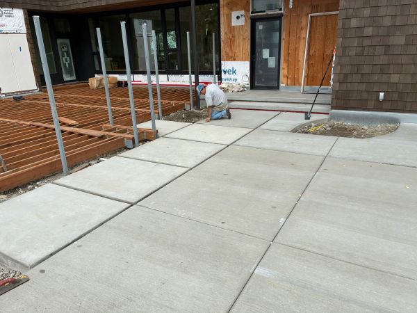 Construction worker working on concrete slabs near a building under construction.