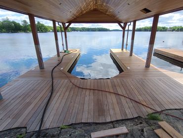 Restored Muskoka wooden boathouse dock with professional wood restoration and refinishing.