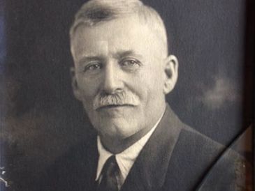 Black and white portrait of an older man with a mustache in formal attire.