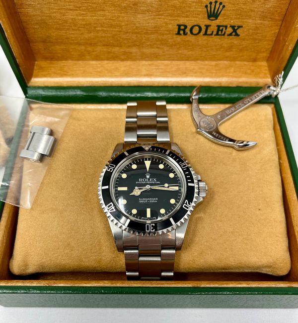 Rolex Submariner watch in a green Rolex box with accessories.