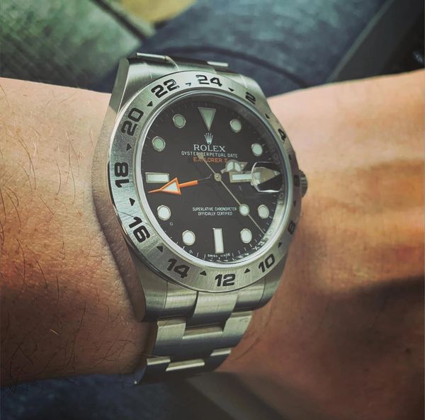 A Rolex Explorer II watch with a black dial on a wrist.