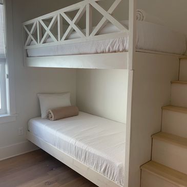 White bunk bed with stairs in a bright room.