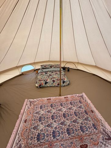 Cozy tent interior with floral bedding and patterned rug.