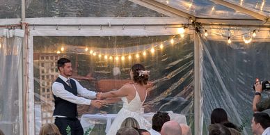 A bride and groom dancing under string lights at a wedding reception.