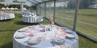 Elegant outdoor wedding tables set under a transparent marquee with floral decorations.
